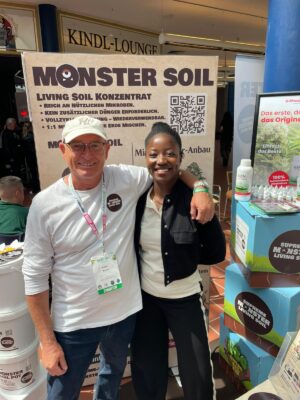 Two visitors at the Monster Soil living soil stand at a trade fair